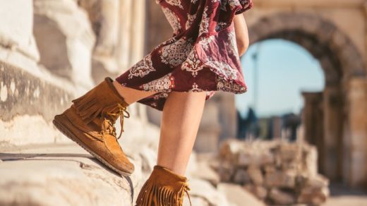 woman in red and black floral dress and brown boots standing on brown concrete floor during